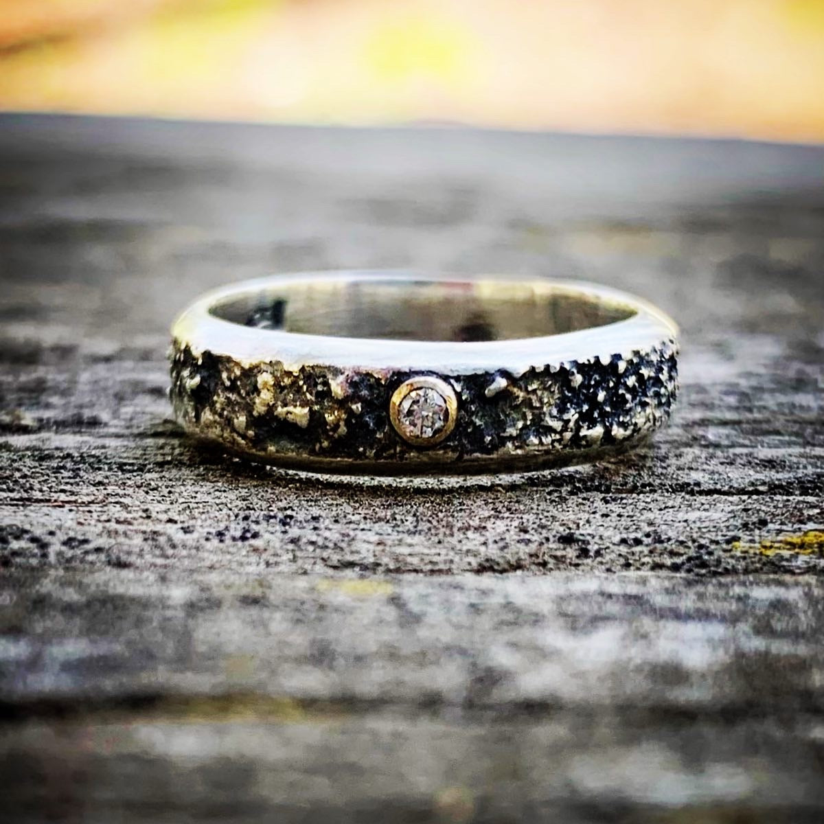 Silver ring with a central gemstone on a textured surface