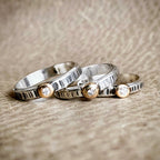 Three silver rings with small diamonds on a textured surface