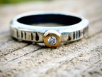 Silver ring with a gold accent and diamond on a wooden surface