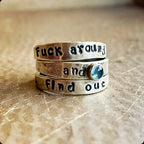 Stack of silver rings with text on a textured surface