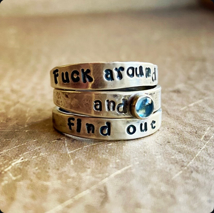 Stack of silver rings with text on a textured surface