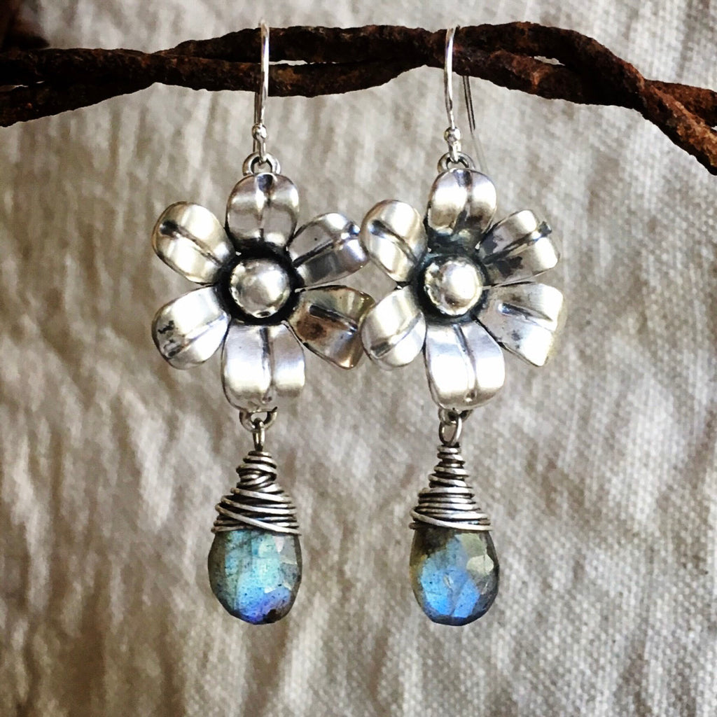 Flower-shaped earrings with Labradorite stones on a textured fabric background