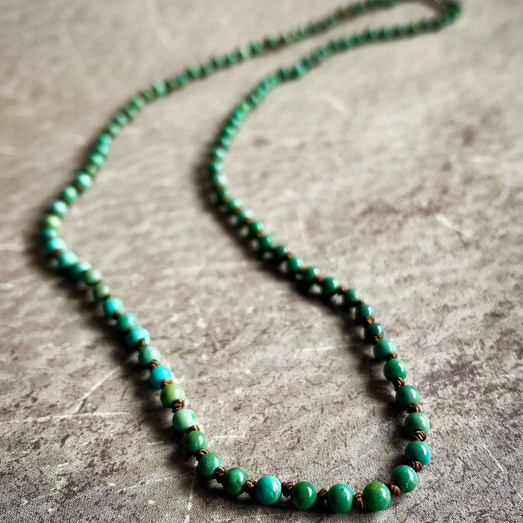 Green beaded necklace on a textured surface