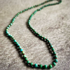 Green beaded necklace on a textured surface