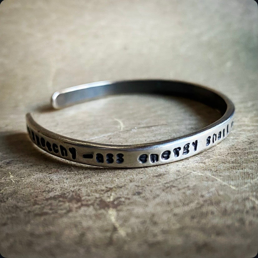 Silver bracelet with engraved text on a textured surface