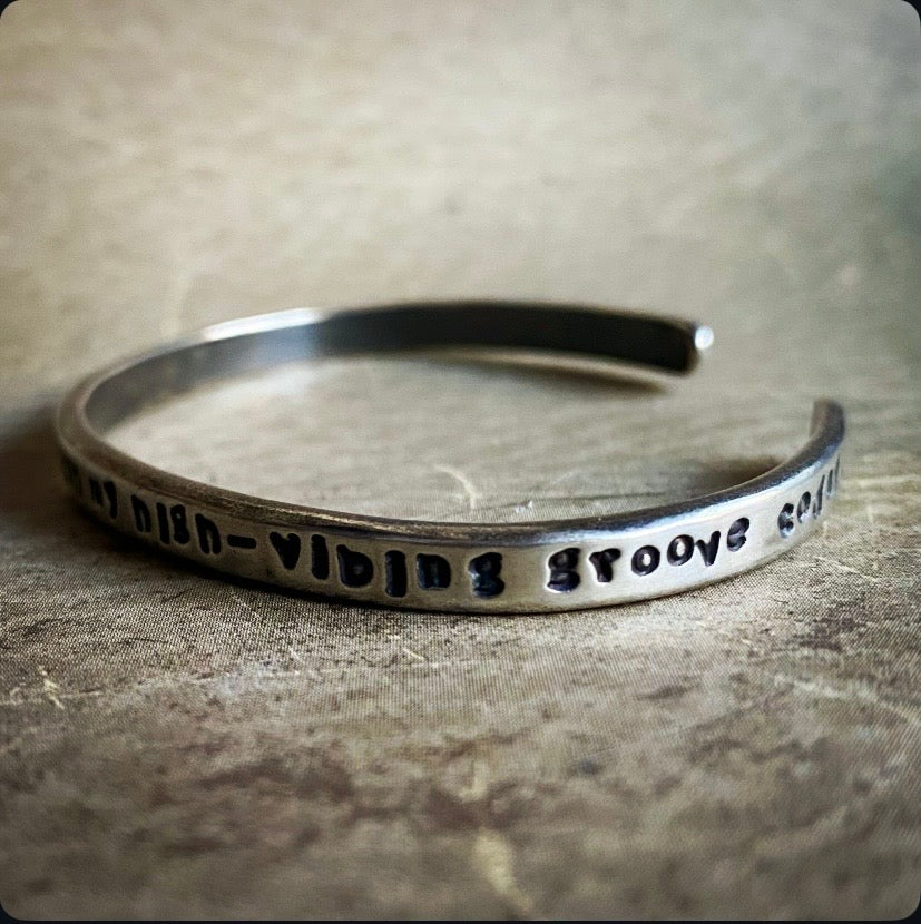Silver bracelet with engraved text on a textured surface