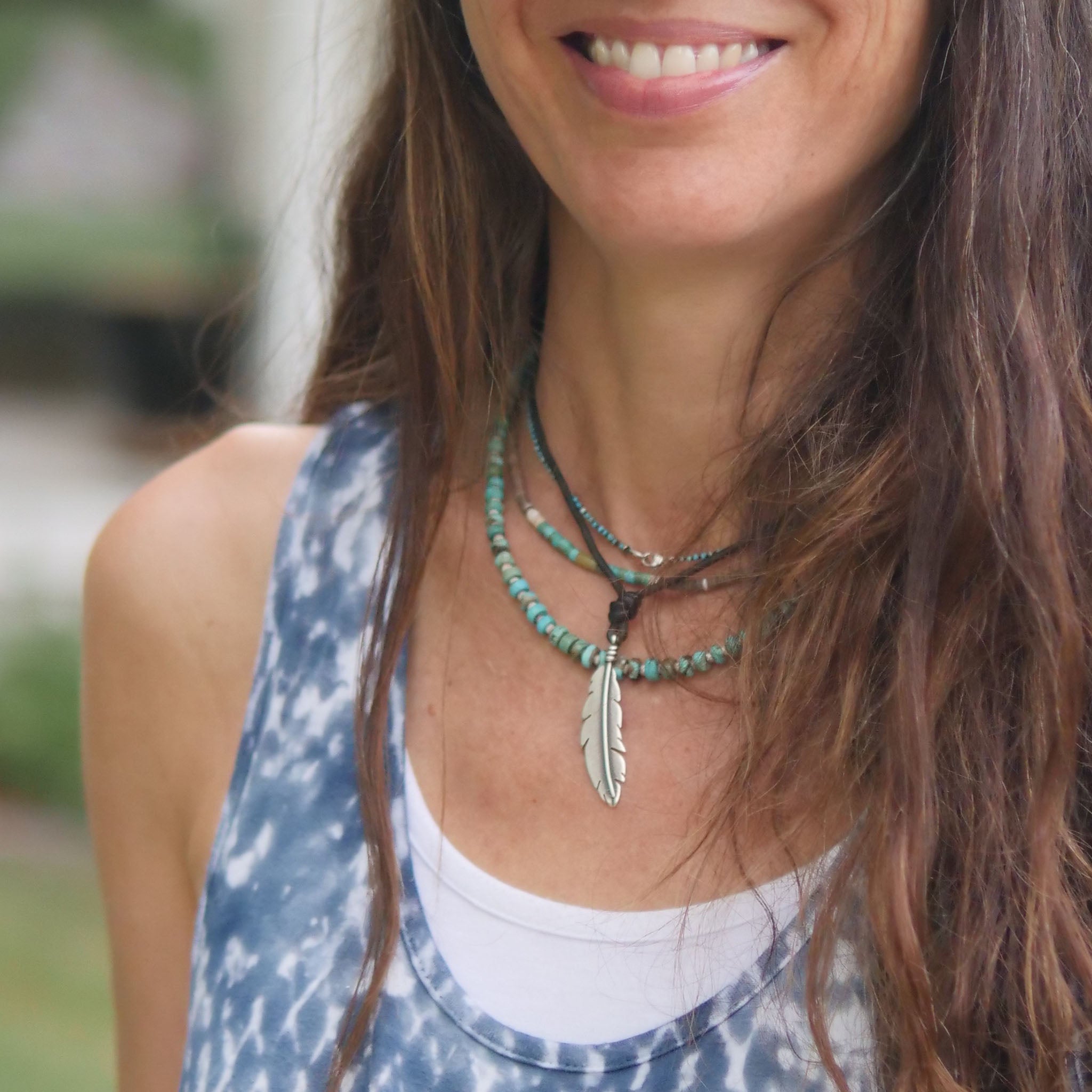 Amy wearing a necklace with a feather pendant outdoors