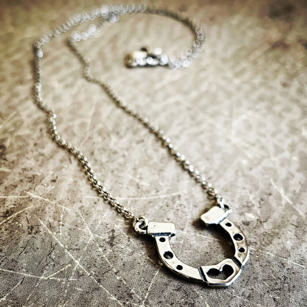 Silver horseshoe necklace on a textured surface