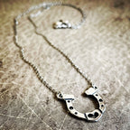 Silver horseshoe necklace on a textured surface