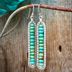Turquoise beaded earrings on a rustic wooden background