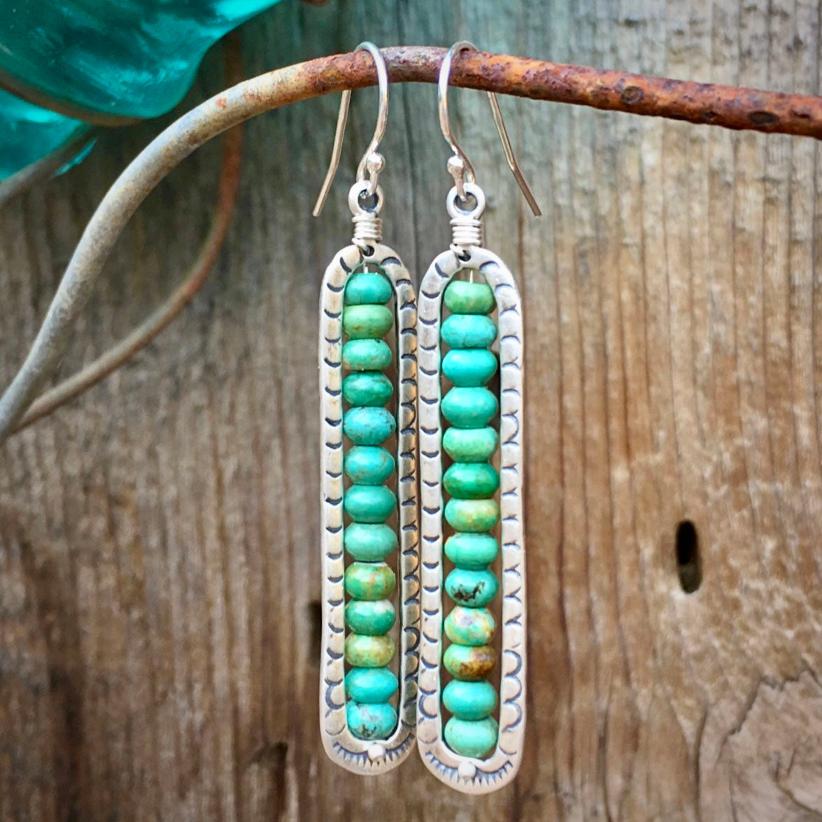 Turquoise beaded earrings on a rustic wooden background
