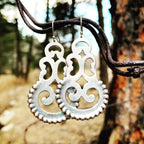 Silver earrings hanging on a branch with a natural background