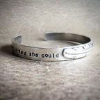 Silver bracelet with engraved text on a textured surface