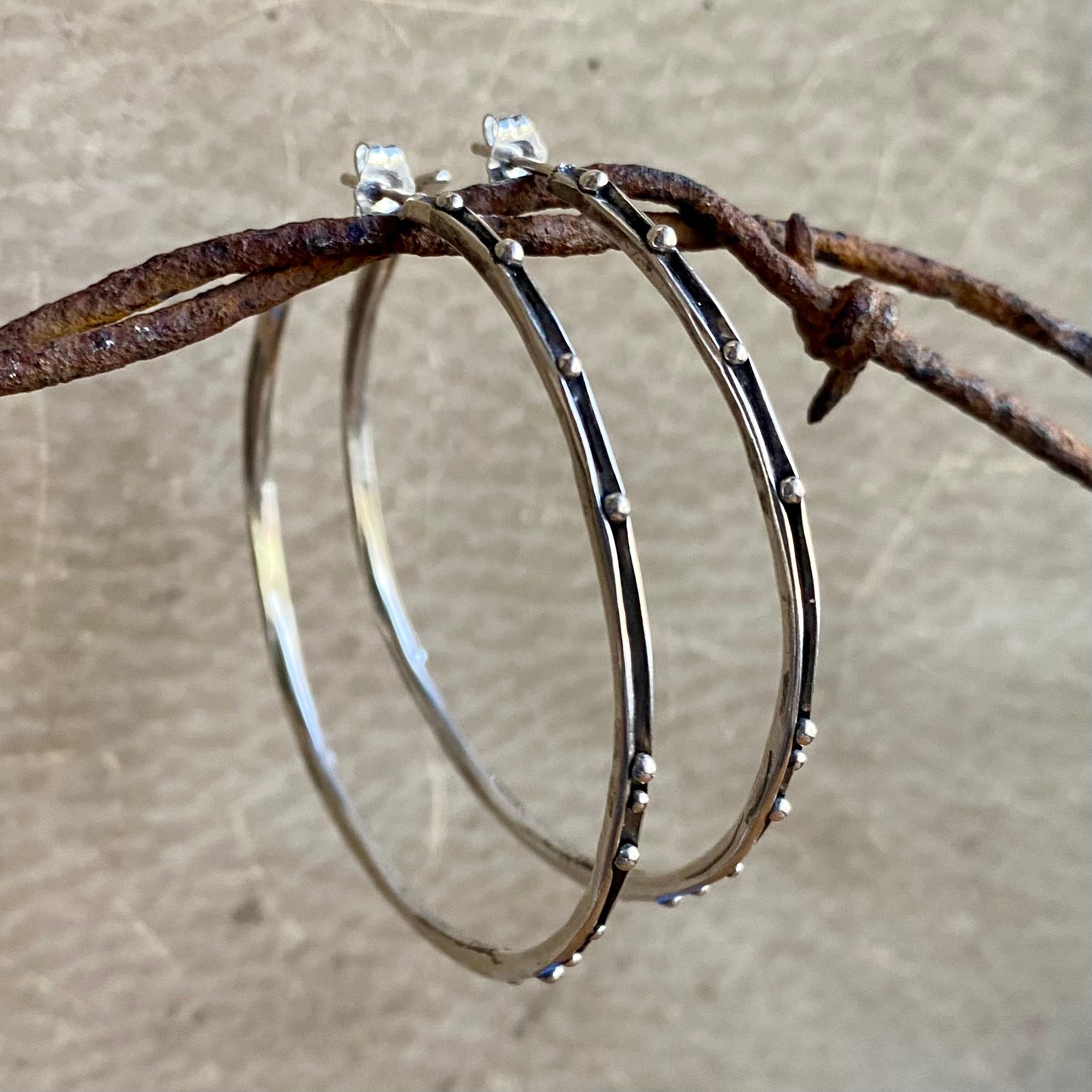 Silver hoop earrings with embedded stones on a rustic background