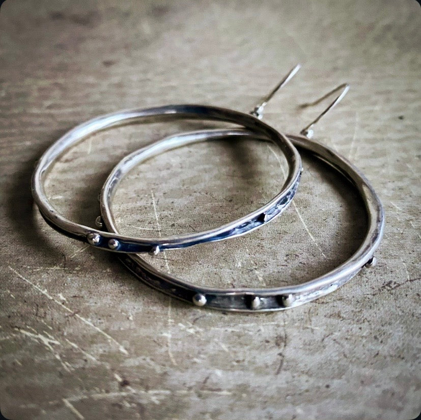 Silver hoop earrings on a textured surface