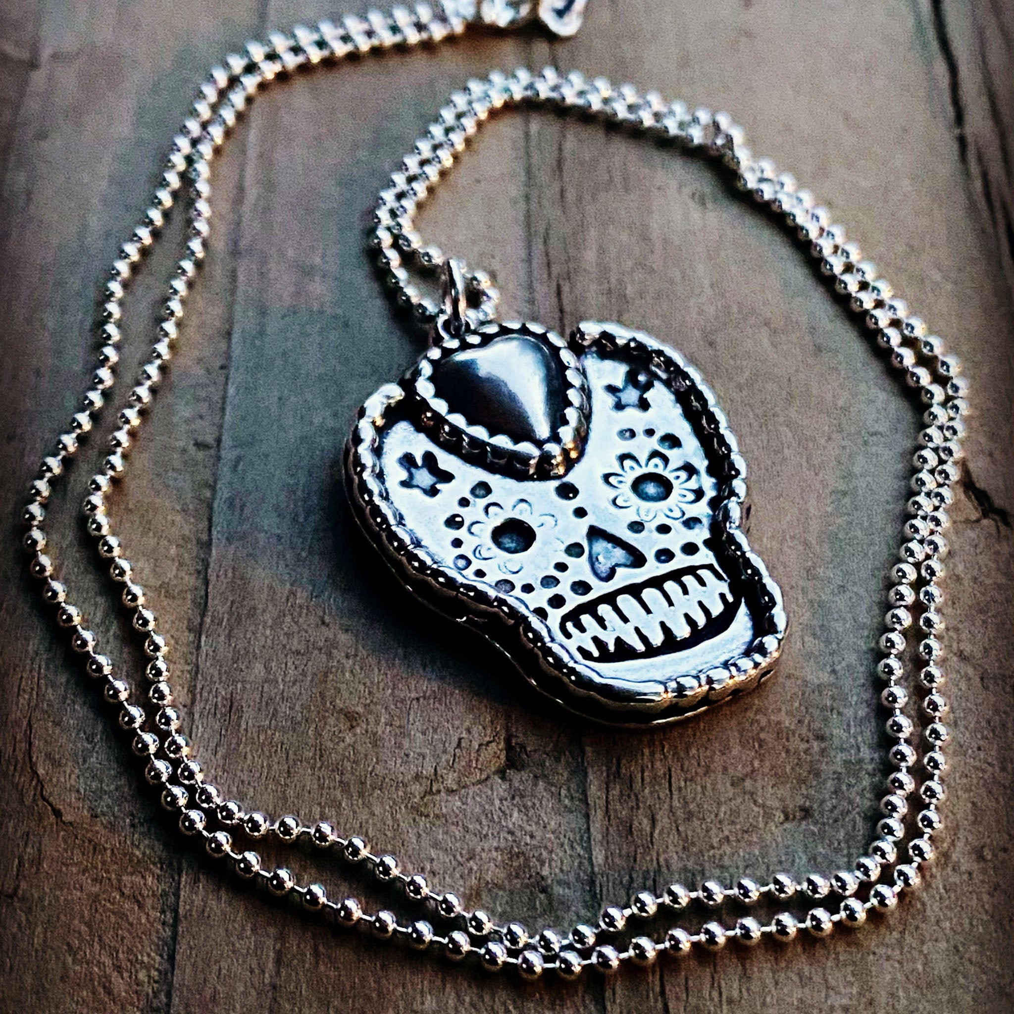 Silver skull pendant necklace on a wooden surface