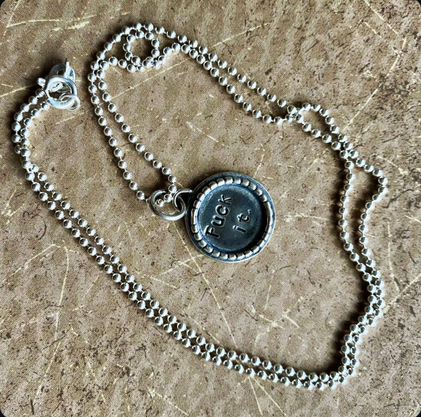 Silver necklace with a pendant on a textured surface