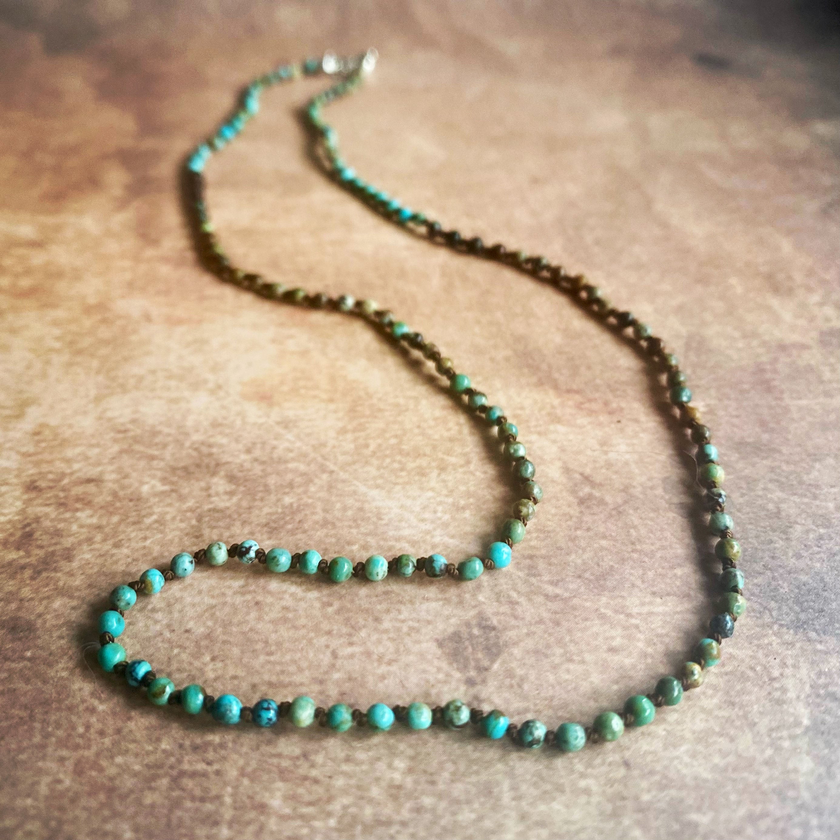 Beaded necklace with green and brown beads on a wooden surface