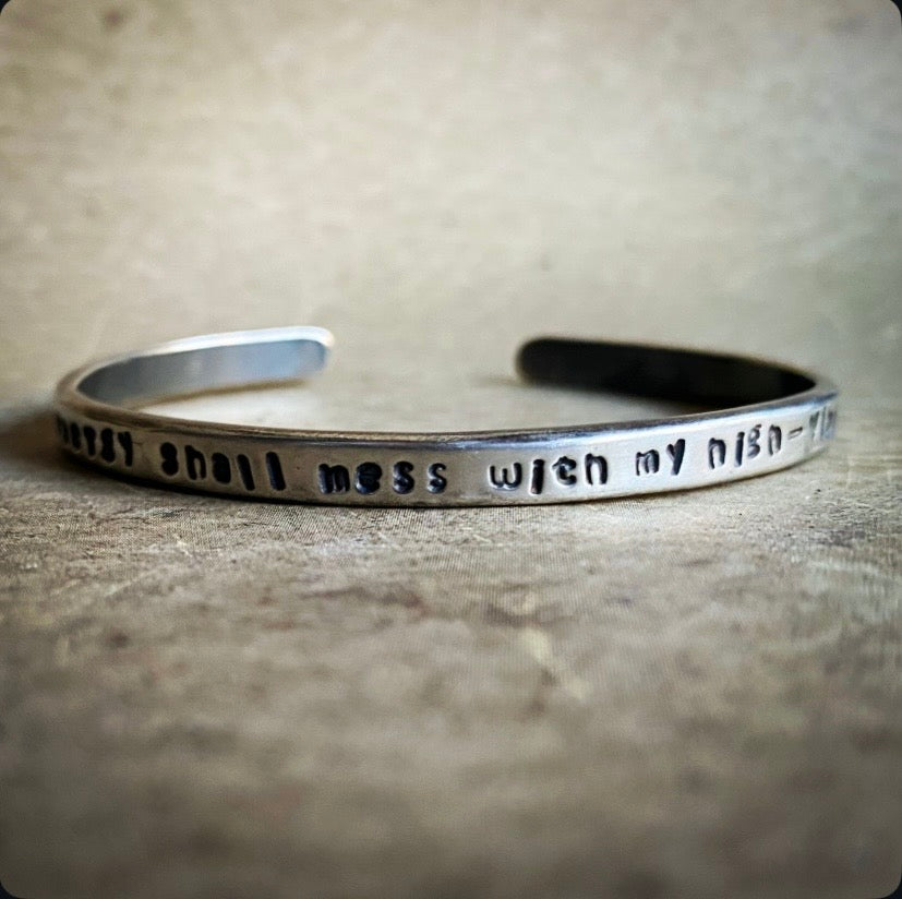 Silver bracelet with engraved text on a textured surface
