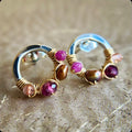 Pair of hoop earrings with gemstones on a textured surface