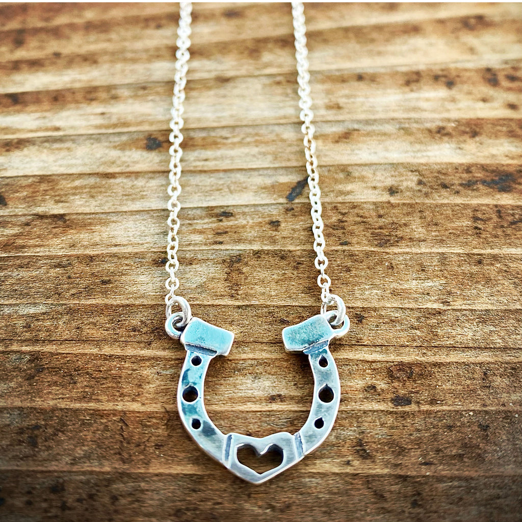 Silver horseshoe necklace on a wooden surface