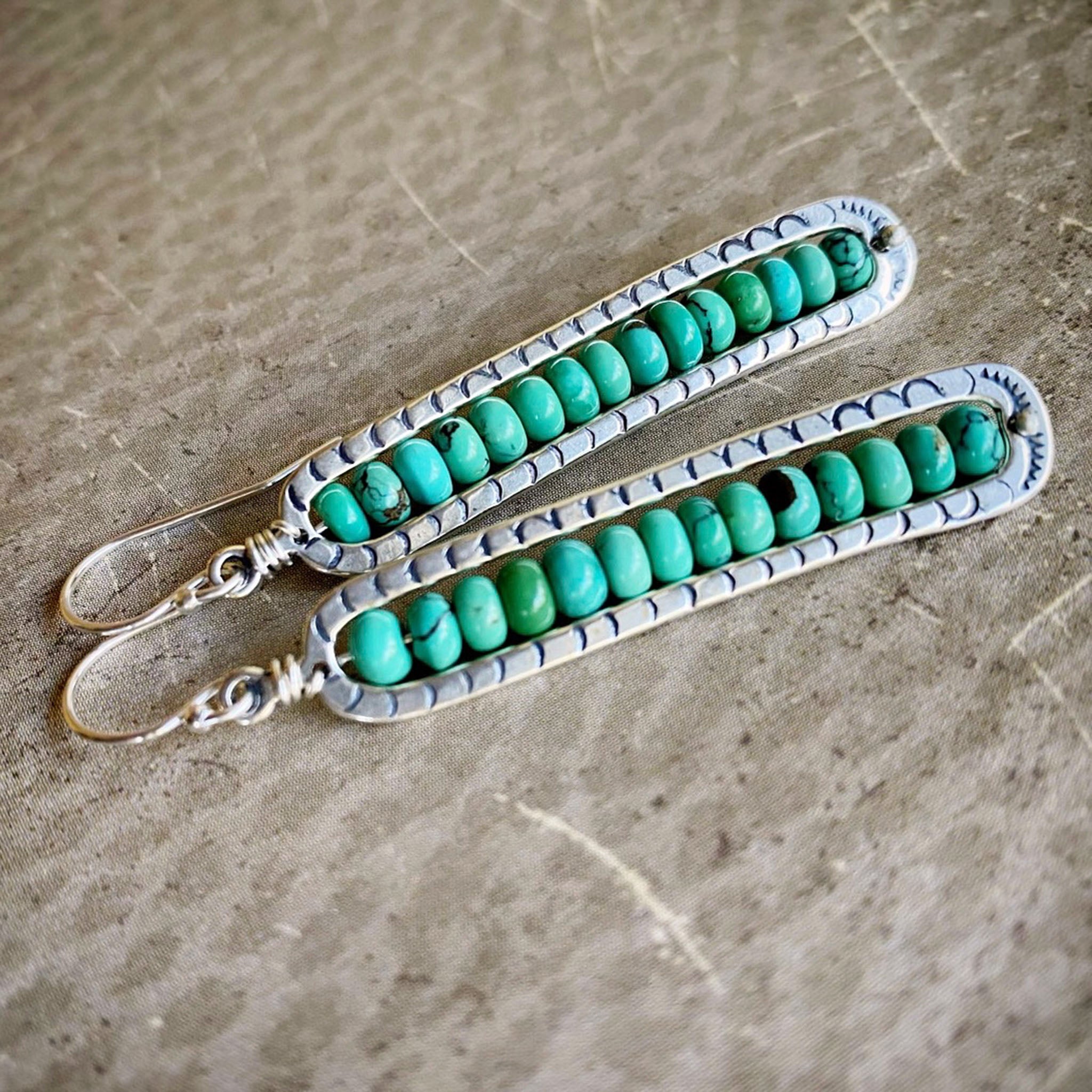 Two turquoise beaded straps on a textured surface