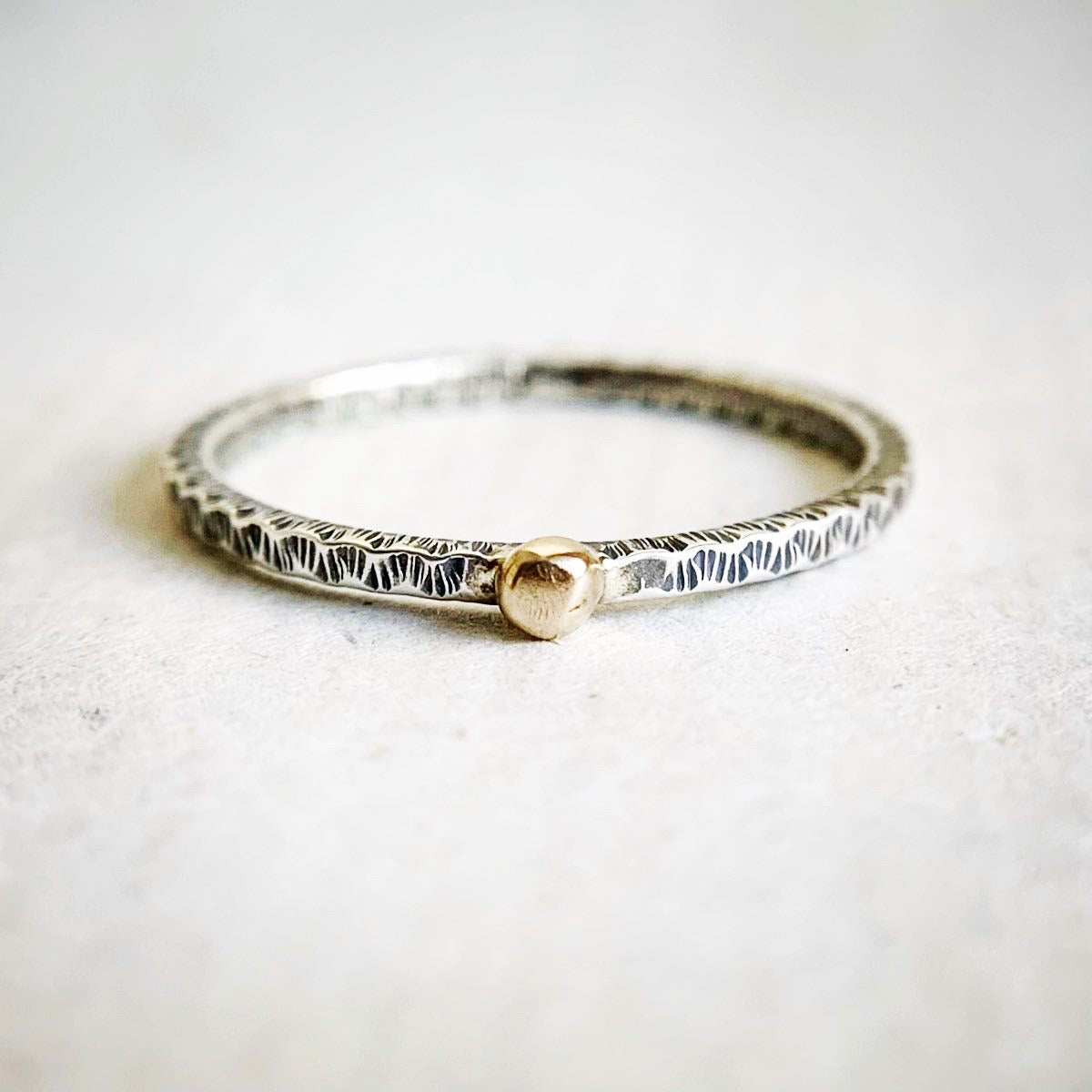 Silver bracelet with a gold clasp on a light gray background