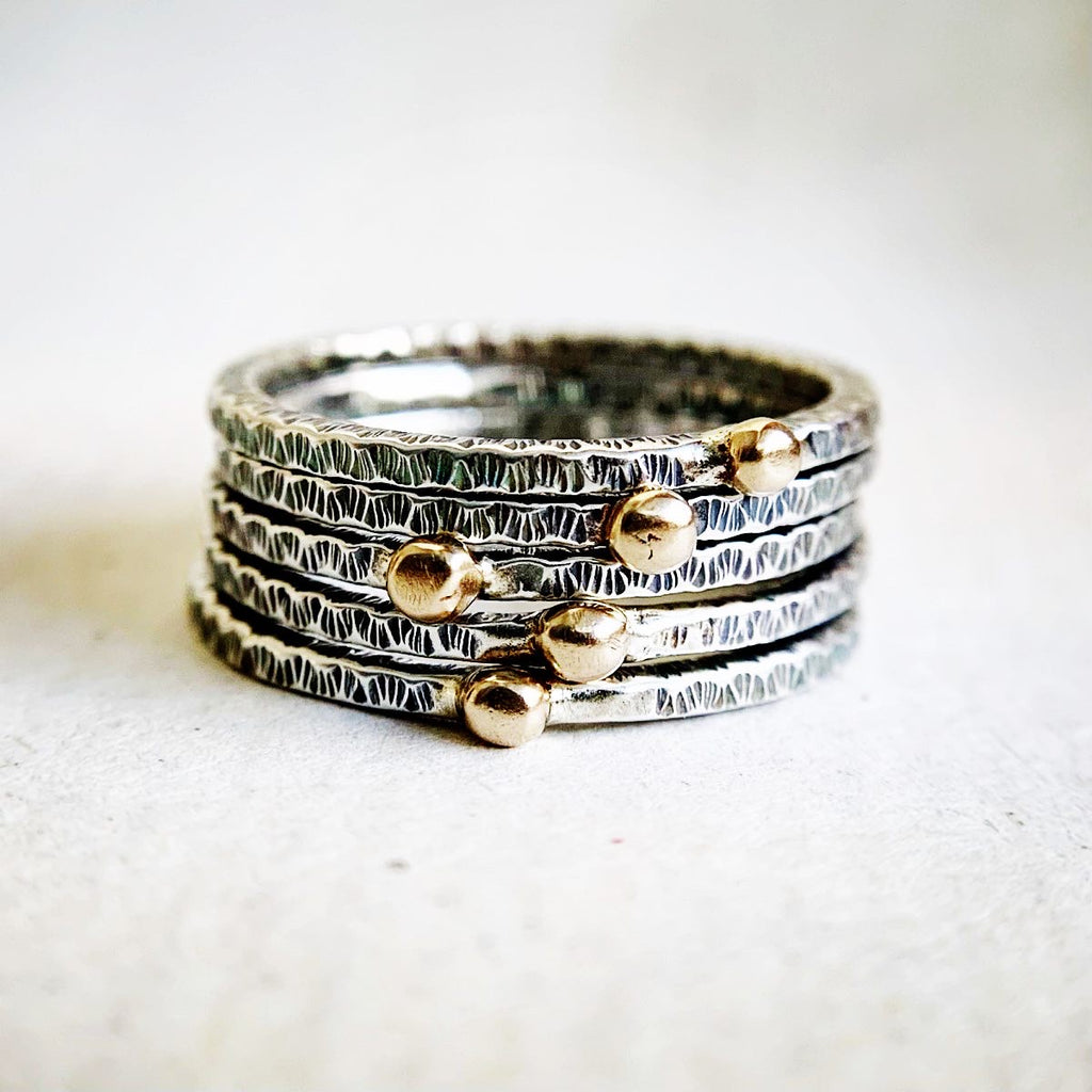 Stack of silver and gold rings on a textured fabric background