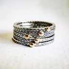 Stack of silver and gold rings on a textured fabric background