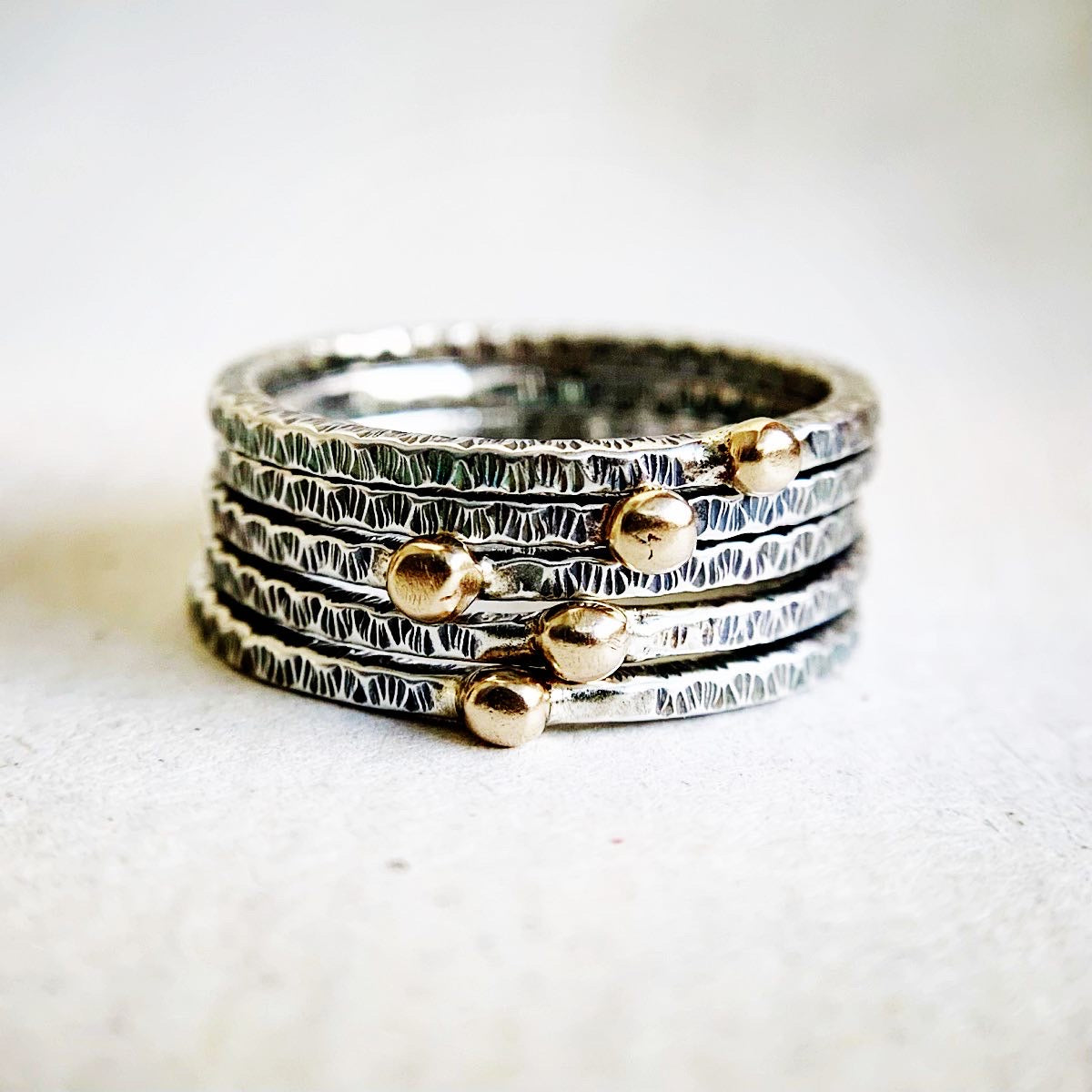 Stack of silver and gold rings on a textured fabric background