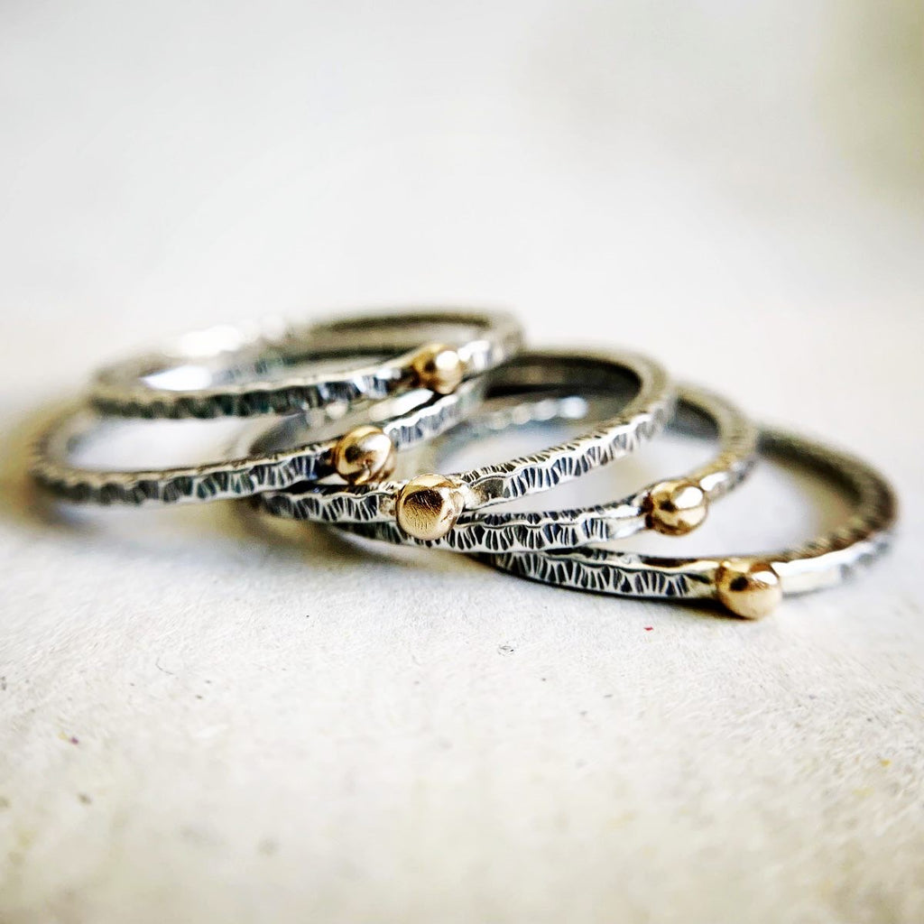 Stack of silver and gold rings on a textured fabric background