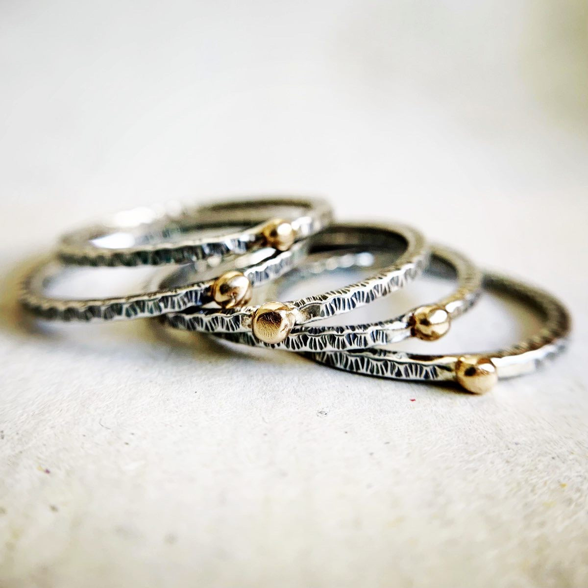 Stack of silver and gold rings on a textured fabric background
