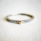 Silver ring with a gold clasp on a light gray background