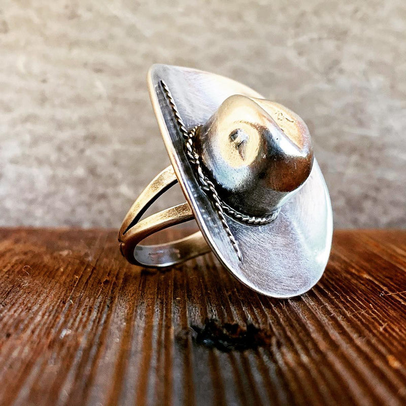 Silver Cowboy Ten Gallon Hat ring on a wooden surface with a neutral background