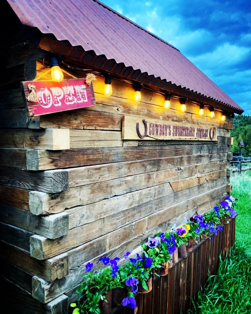Wooden building exterior with 'Open' sign and cowboy-themed decor