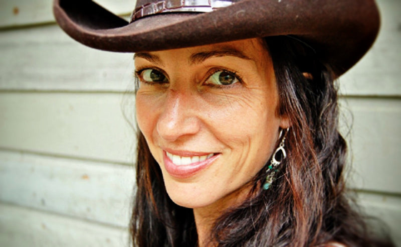 Amy wearing a brown cowboy hat against a neutral background